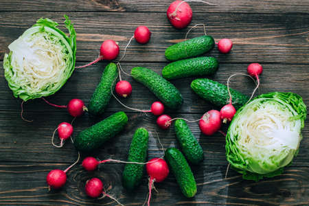 Cabbage with cucumbers and radishes top view on a background of wooden boards.の写真素材