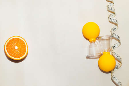 Vacuum massage anti-cellulite cups on a gray background with an orange and centimeter. Self-massage for healthy skin.の写真素材