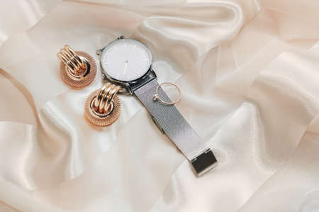 Women's jewelry earrings, trendy jewelry, watches, rings on a silk background.の写真素材