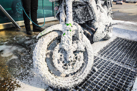 A man washes a motorcycle. Special wash foam removes dirt.の写真素材