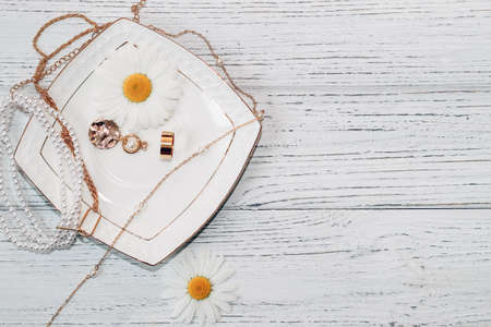 Delicate daisies close-up with gold jewelry. Chains, pendants, rings on a stand.の写真素材