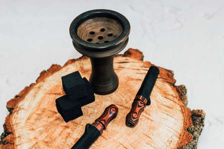 Clay bowl for hookah with coconut coals, wooden mouthpieces stands on a white background.の写真素材