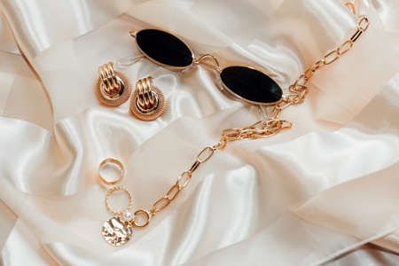 Flatley with gold jewelry and pearls on a silk background, glasses in the frameの写真素材