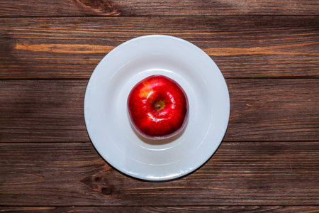 Apple on an empty white plate. Diet and raw food concept.の写真素材