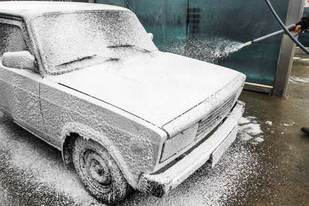 A man washes a white car. Special wash foam removes dirt.の写真素材