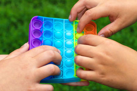 Ukraine, Cherkassy - June 18, 2021: Child's hands are played square multicolored bubble toy antistress sensory pop itのeditorial素材