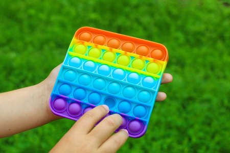 Ukraine, Cherkassy - June 18, 2021: Child's hands are played square multicolored bubble toy antistress sensory pop it.のeditorial素材
