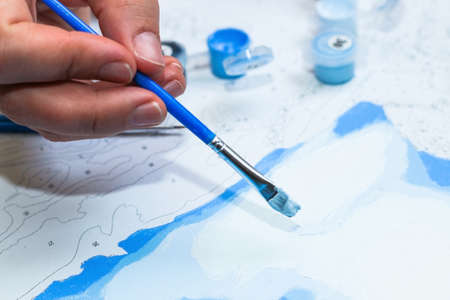 Girl paints with acrylic brush by Number Kits.の写真素材