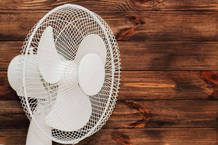 White fan with blades for cooling the room in the heat on a wooden background.の写真素材
