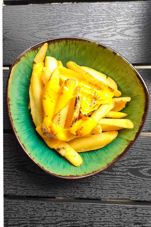 Delicious French fries with cheese in a green plate in a restaurant.の写真素材