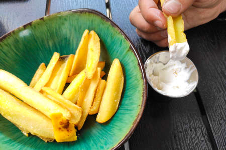 Delicious French fries with cheese in a green plate in a restaurant.の写真素材