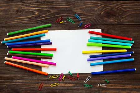 School creative flatley. On a wooden table are multi-colored felt-tip pens and a sheet with empty space for text.の写真素材