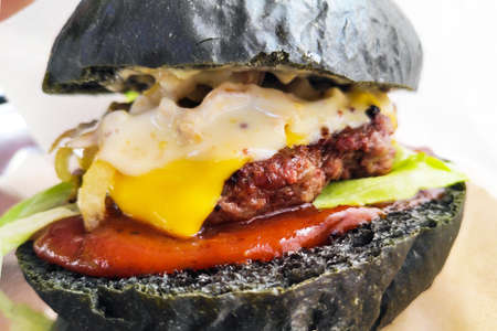 Burger with black buns close-up. Appetizing street food.の写真素材