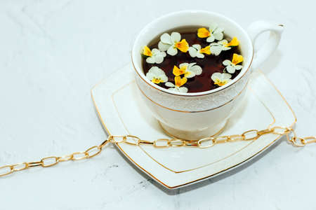A beautiful white cup with a gold border, decorated with flowers and gold jewelry. Business account design.の写真素材