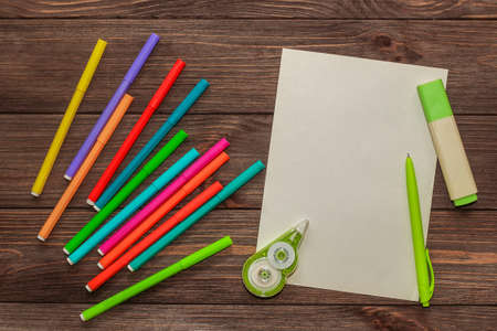 School creative flatley. On a wooden table are multi-colored felt-tip pens and a sheet with empty space for text.の写真素材