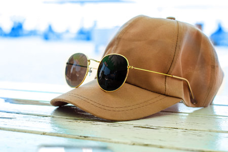 sun baseball cap with glasses on a wooden table against the background of the sea.