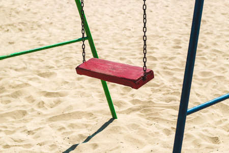 red wooden swing at playground on sand background.の写真素材