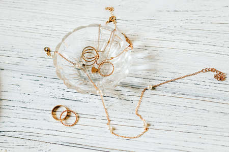Gold jewelry rings, bracelet, chain in a crystal saucerの写真素材