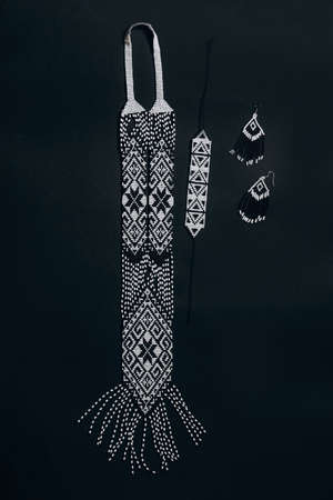 White and black traditional gerdan with handmade beaded earrings on a black background.の写真素材