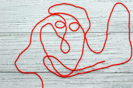 Red beads on a wooden white background. Beads and handicrafts for creativity.の写真素材