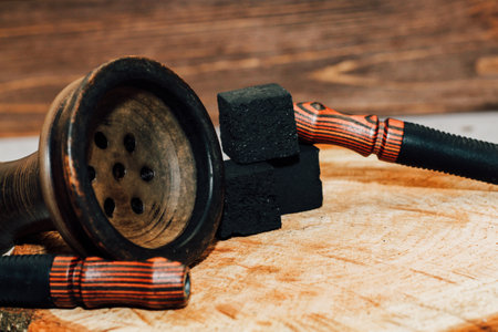 Clay bowl for hookah with coconut coals, wooden mouthpieces stands on a wooden background.の写真素材