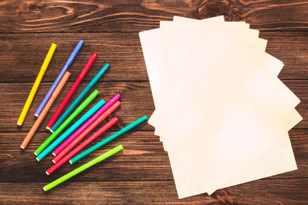 School creative flatley. On a wooden table are multi-colored felt-tip pens and a sheet with empty space for text.の写真素材
