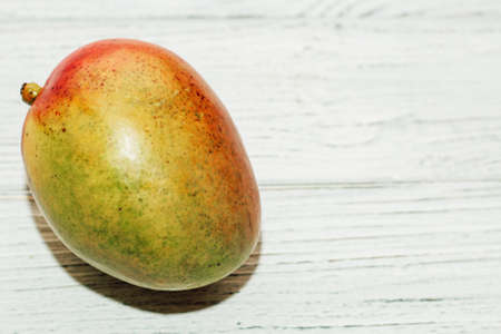 ripe juicy mango lies on a wooden white table.の写真素材