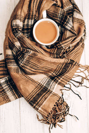 White cup with coffee with milk on the background of an autumn checkered plaid.の写真素材