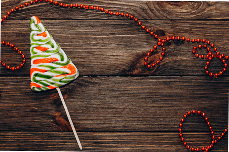 Wooden planks background together with red beads and christmas tree lollipop.の写真素材