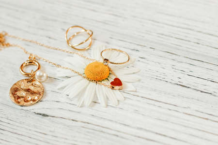 Delicate daisies close-up with gold jewelry. Chains, pendants, rings on a stand.の写真素材