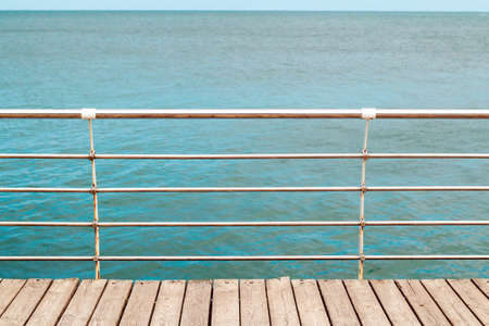 embankment from wooden boards railing on a blue sea background on the water surface.の写真素材