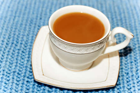 White cup and saucer with coffee with milk on the background of a knitted sweater.の写真素材