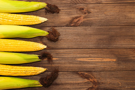 Sweet yellow corn lies on a wooden table.