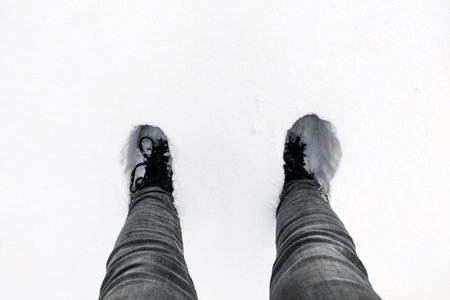 Snow-covered uncleared white road with deep human footprints.