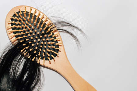 Wooden comb with fallen hair on it and scissors.の写真素材
