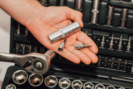Hands holding tools wrench and nuts on the background of a box for a motorist.の写真素材