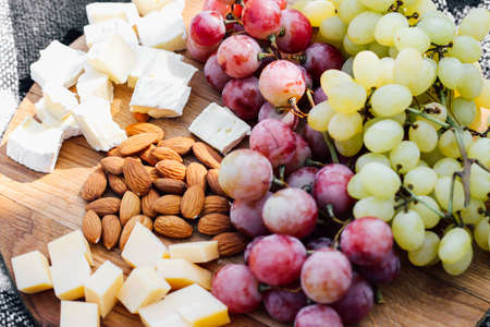 Wooden board with fruits, cheese, nuts, picnic snacks.の写真素材