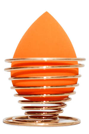 Cosmetic sponge sponge for applying makeup on a golden stand isolated on a white background.の写真素材
