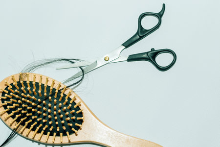 Wooden comb with fallen hair on it and scissors.の写真素材