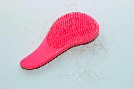Comb plastic roses with fallen hair on paper background.の写真素材