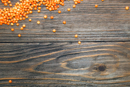 Red lentils scattered on a wooden background.の写真素材