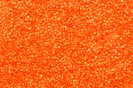 Red lentils scattered close-up, grain texture.の写真素材