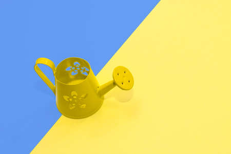 Green iron small watering can on paper blue yellow background.の写真素材