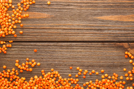Red lentils scattered on a wooden background.