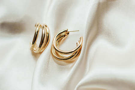 Gold jewelry earrings made of gold on the background of silk.の写真素材