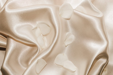 White rose petals on a silk beige background, space for text.