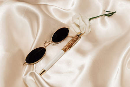Glasses and a pen on a silk beige background, space for text.の写真素材