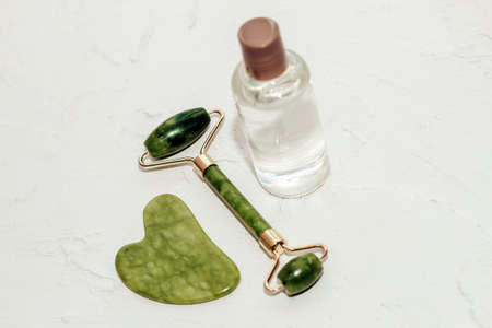 massage stone jade gouache scraper and facial roller with cosmetic cream.の写真素材