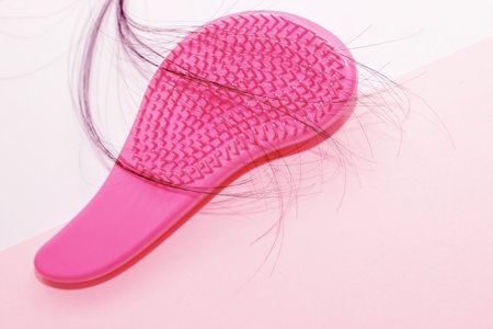 Comb plastic pink and fallen hair on a cardboard background.の写真素材