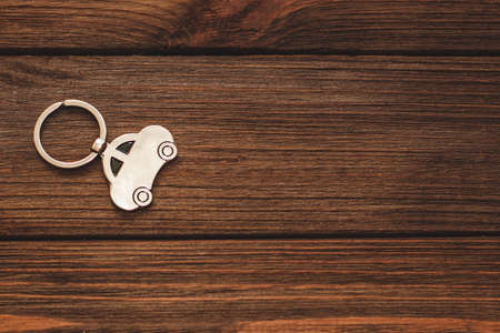 The keychain with a picture of a car in the shape of a house on a wooden background.の写真素材